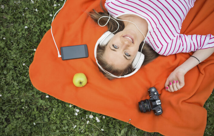 Vrouw met koptelefoon op, liggend in het gras